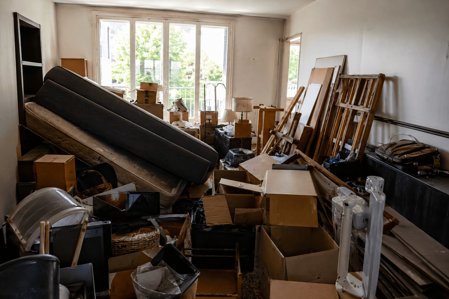 Salon encombré de meubles, cartons et encombrants avant l'intervention de Vide-Express à Bruxelles